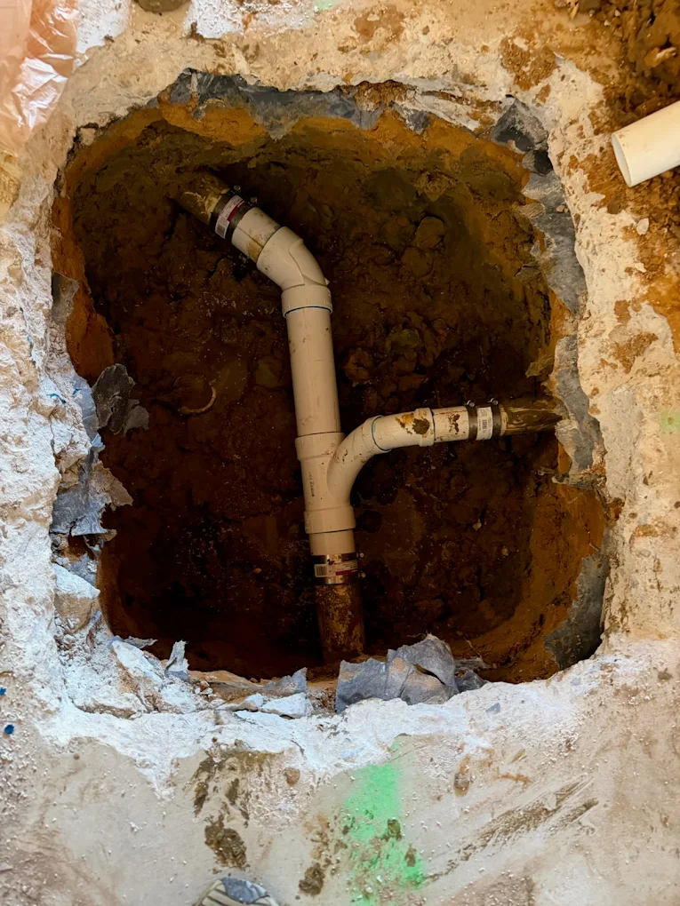 Underground drain pipe repair with exposed PVC plumbing beneath a concrete slab in Aledo, TX